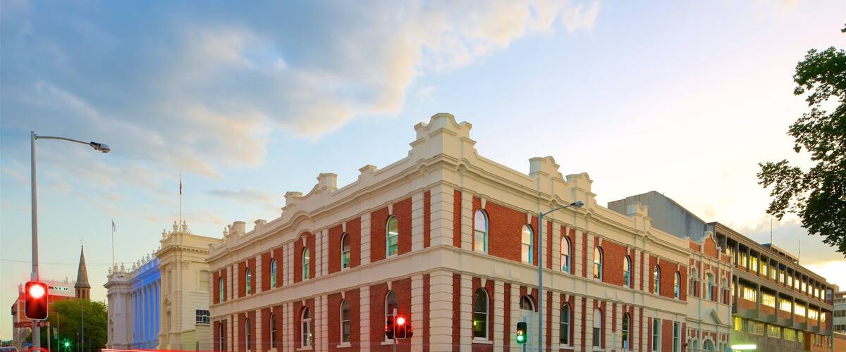 A historic building with red brick and white trim, located at a street corner with traffic lights and a speed limit sign.