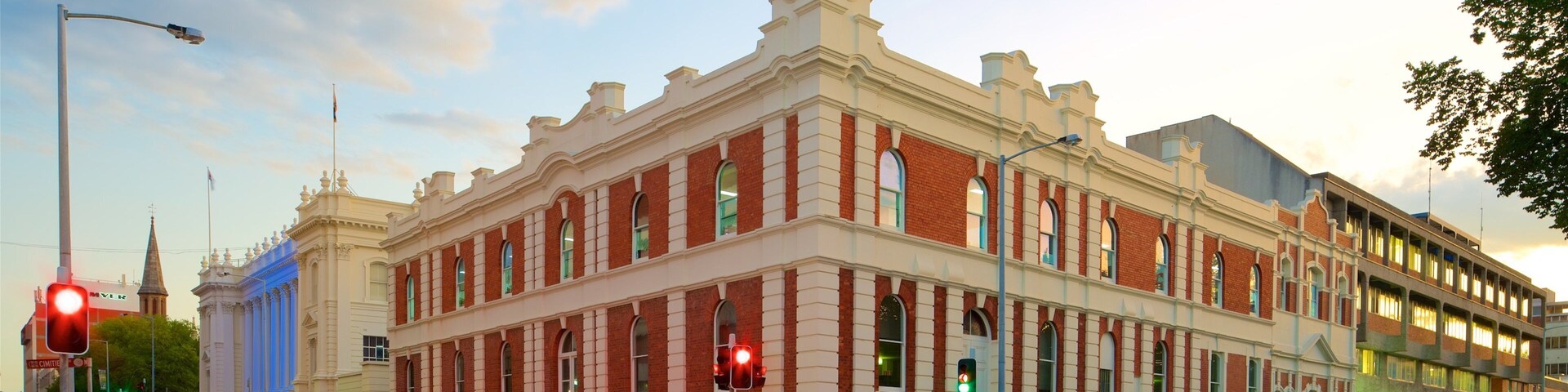 A historic building with red brick and white trim, located at a street corner with traffic lights and a speed limit sign.