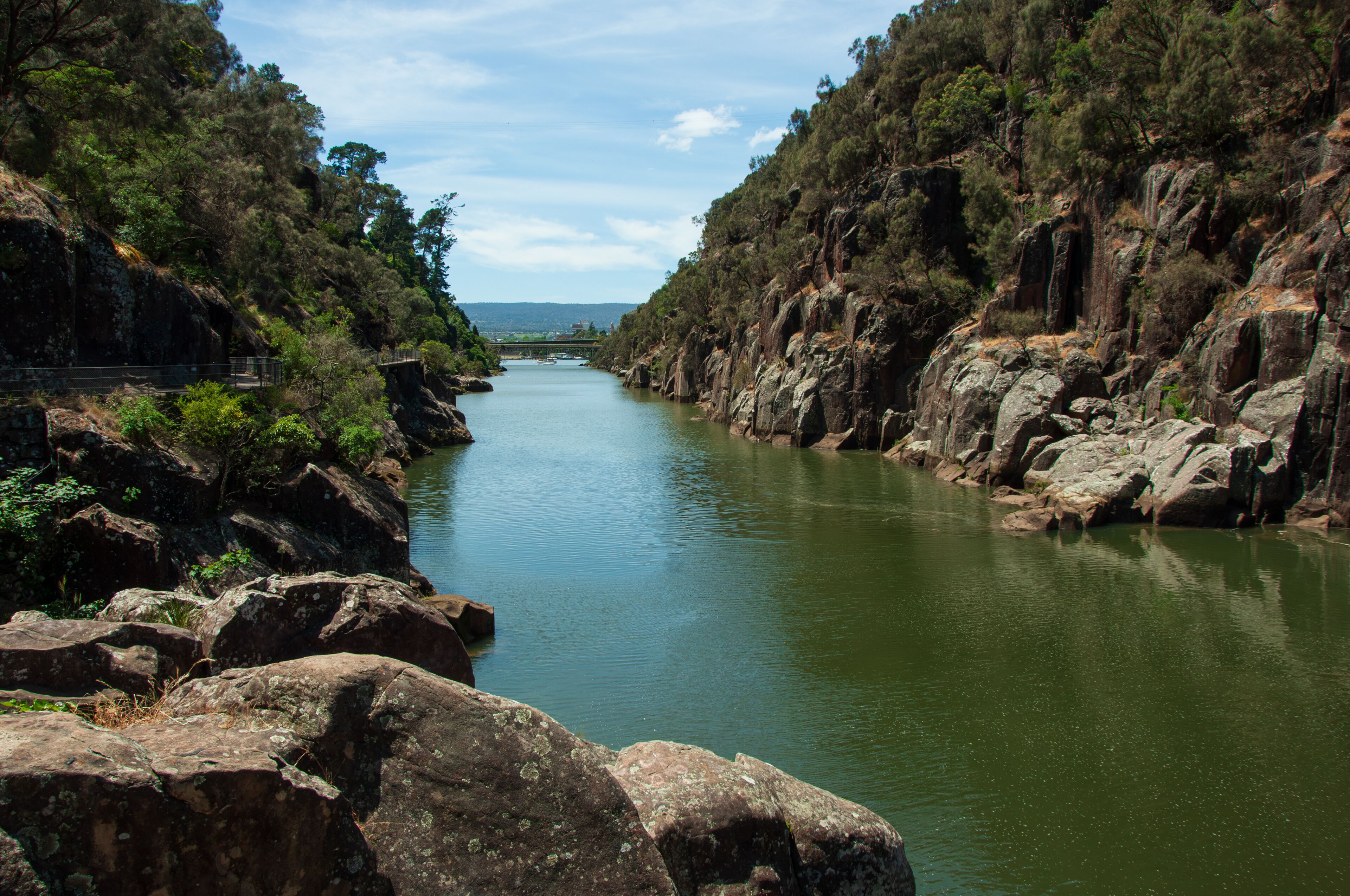 A river flanked by rocky cliffs and dense greenery.