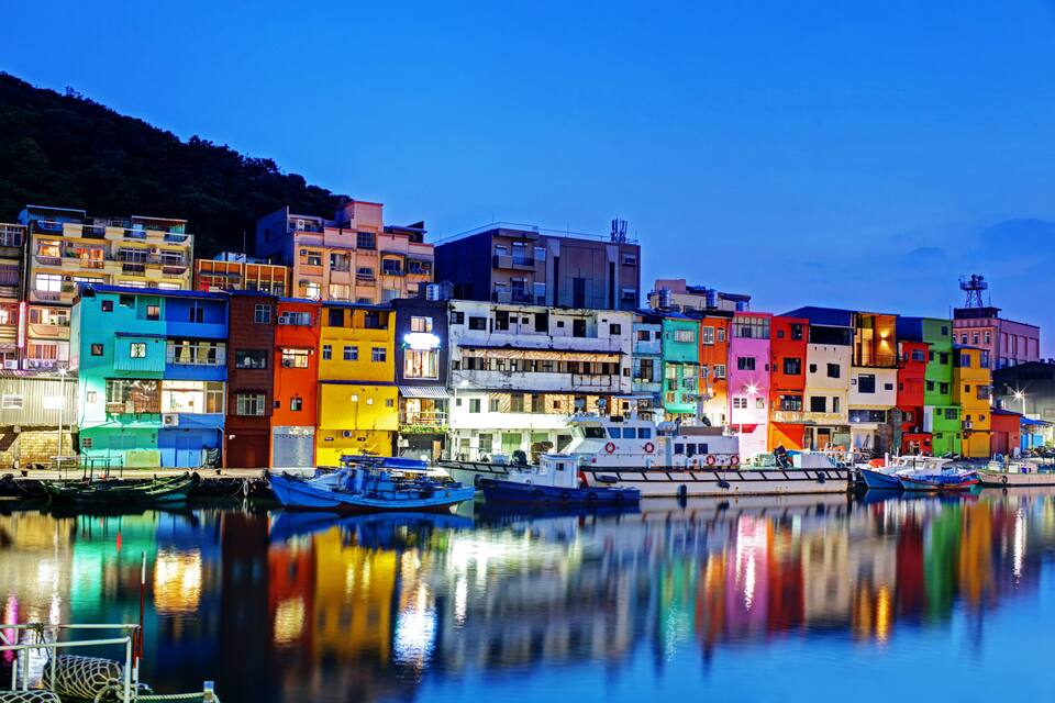 Una passeggiata lungomare con edifici colorati e barche.