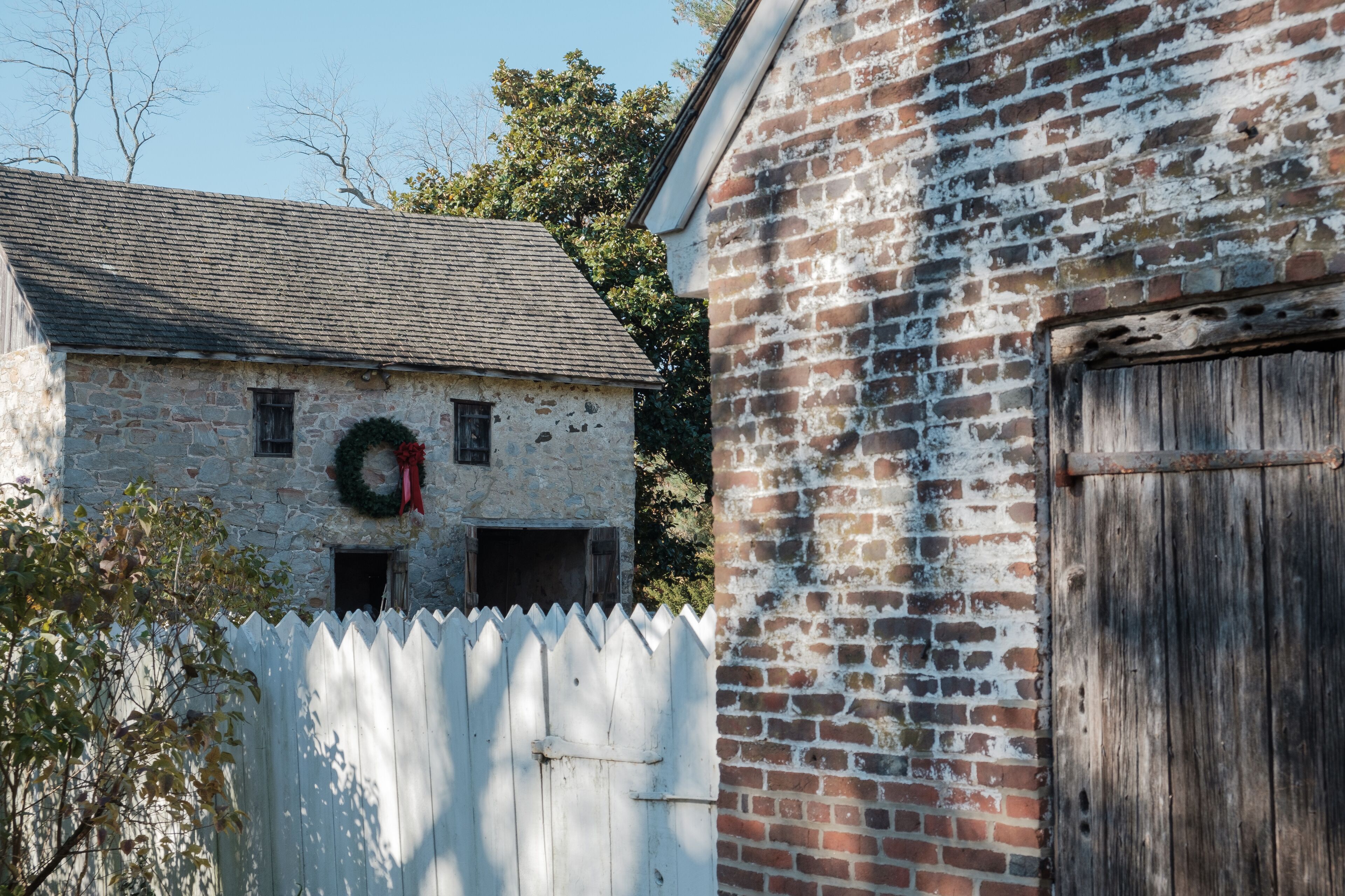 A stone building with a wooden door and a brick wall.