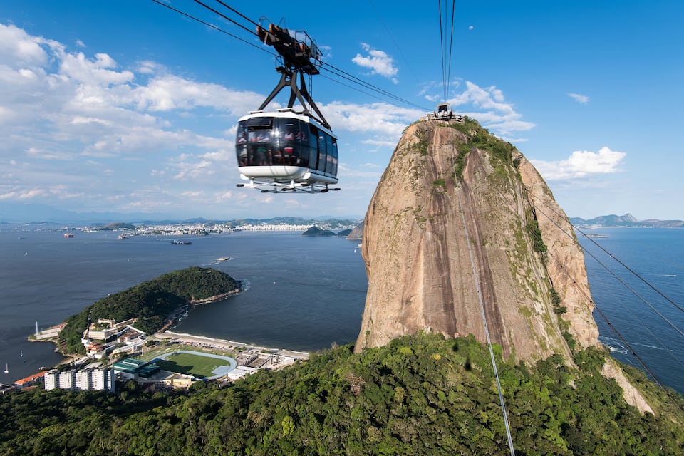 A cable car system, a large mountain, and a coastal cityscape.