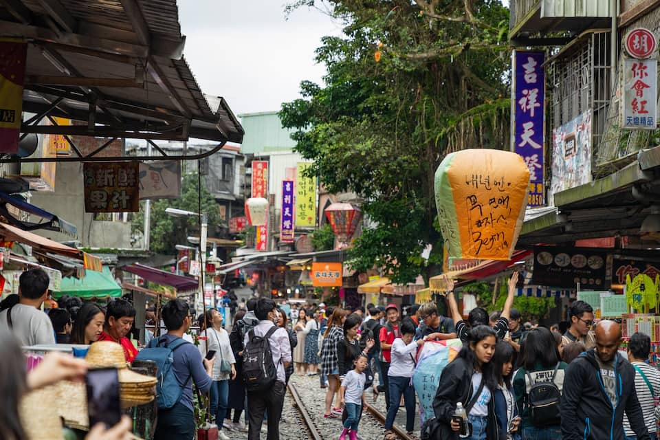 A crowded street market with various shops and signs.