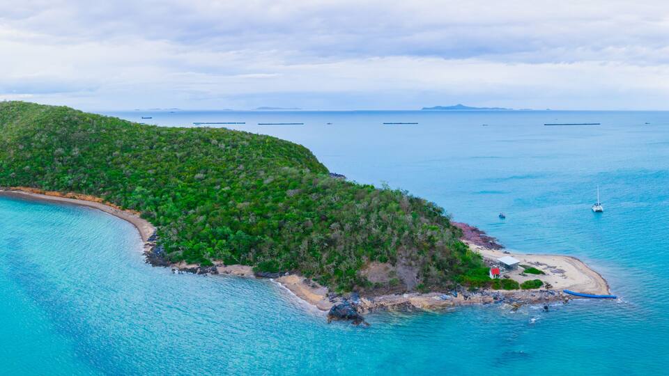 An island with a beach and a forested hill.