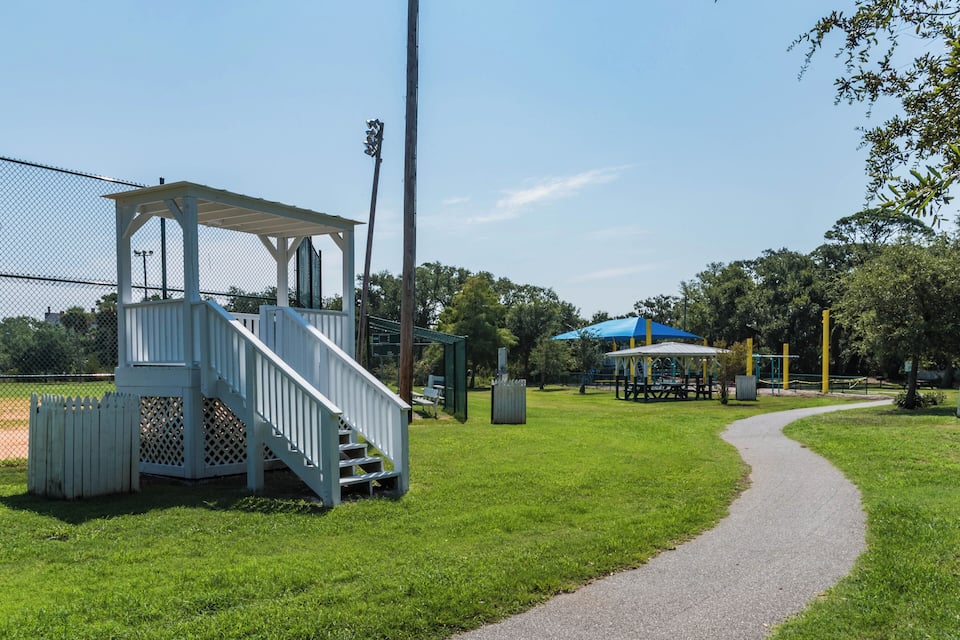 A park with a white gazebo, a blue covered picnic area, and a walking path.