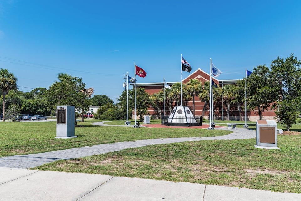 A building with multiple flags, a monument, and a pathway.