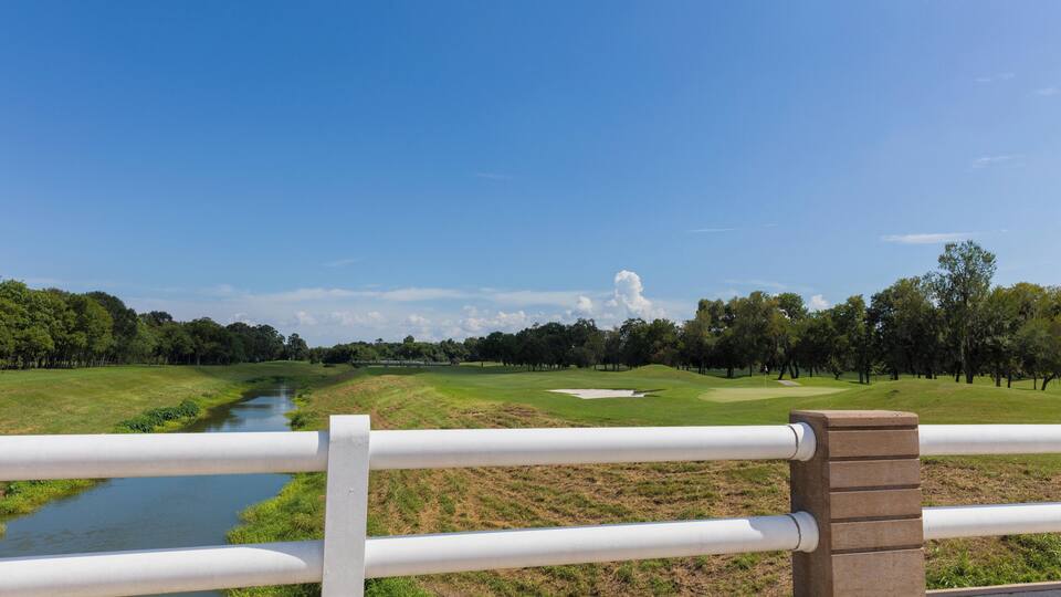 A golf course with a river, trees, and a clear blue sky.