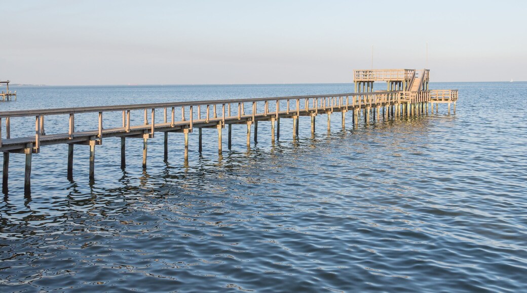 Fishing piers stretching out over Galveston Bay in Kemah, Texas, USA. Foot pier for saltwater fishing of vacation home/beach house rental/bay home in Lighthouse District waterfront at sunset. Panorama