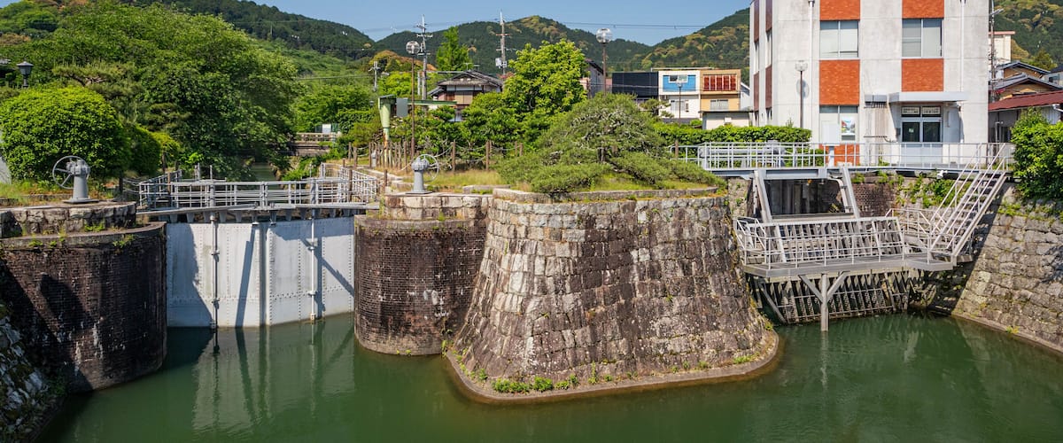 A lock system with water gates, a bridge, and a modern building with orange and white colors.