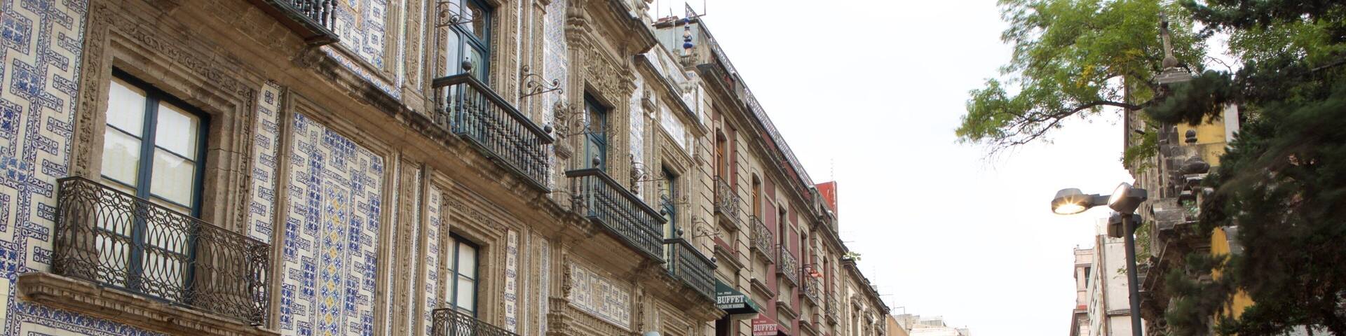 A bustling street with ornate buildings, a crowd of people, and a shop with dolls.