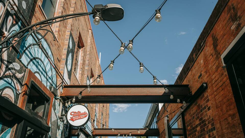 Une enseigne de bar sportif, un lampadaire et un bâtiment avec une horloge.