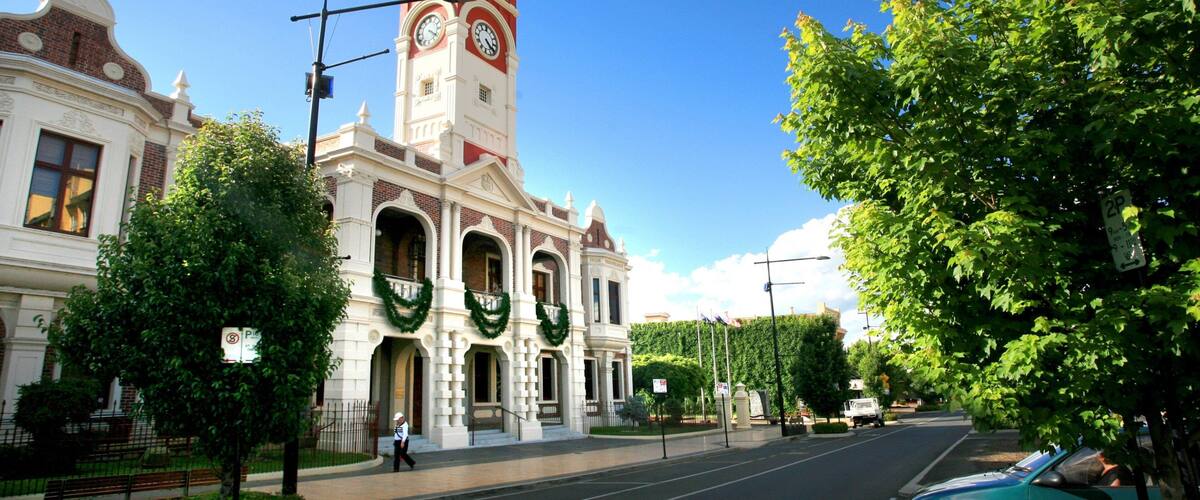 A historic building with a clock tower, surrounded by trees and a clear blue sky.