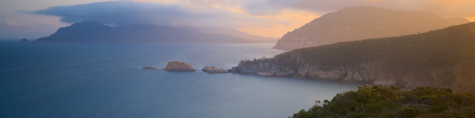 Coles Bay mostrando litoral rochoso, paisagens litorâneas e um pôr do sol