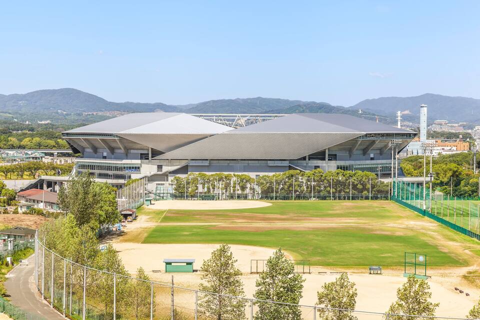 A baseball stadium with a large field and a modern building.