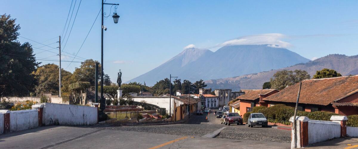 A street with buildings, cars, and a mountain in the background.