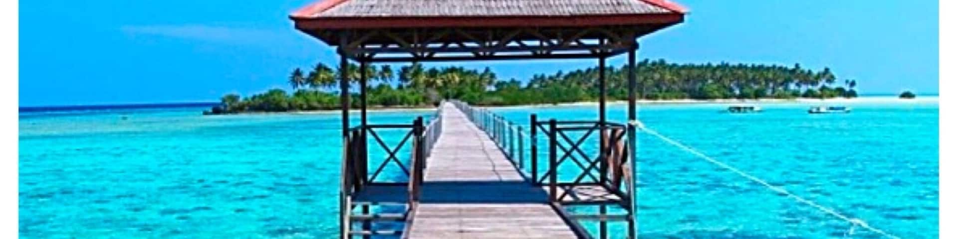 A wooden pier leading to a thatched-roof structure over turquoise waters.
