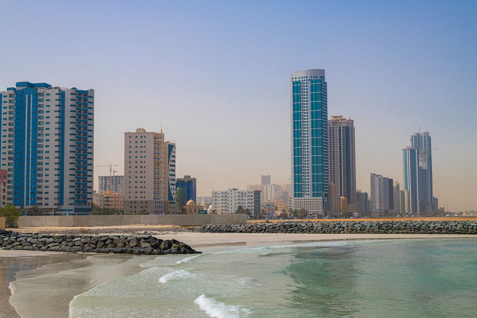A coastal cityscape with high-rise buildings and a sandy beach.