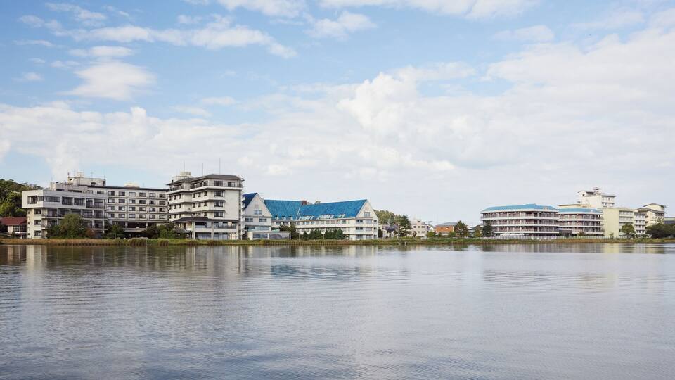 A calm lake with buildings in the background.