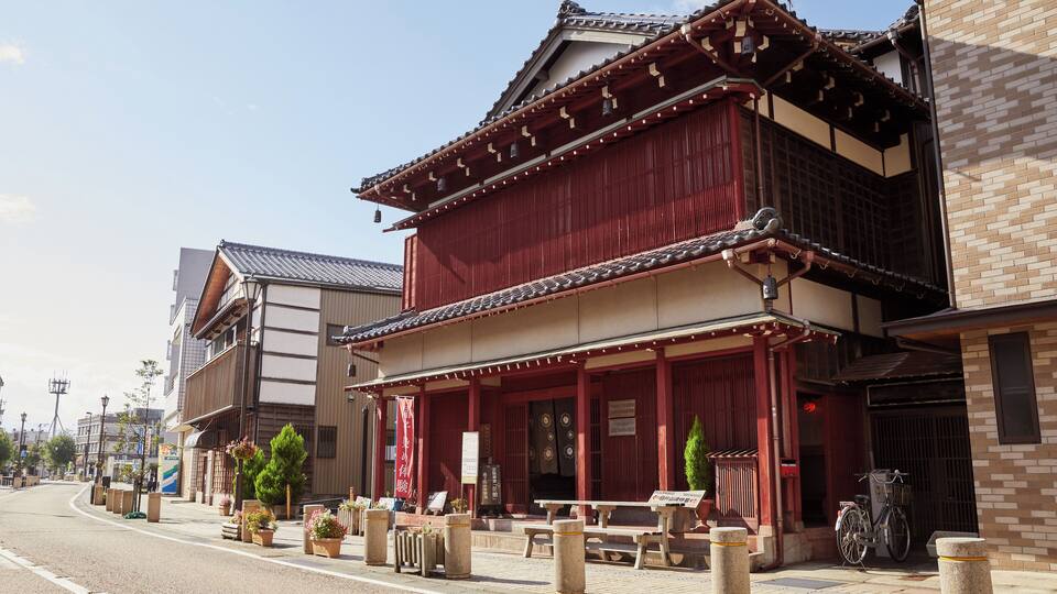 A traditional Japanese building with a red facade, wooden beams, and a tiled roof.