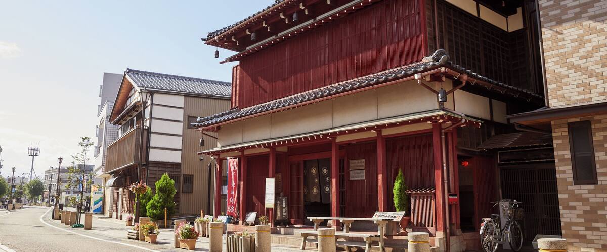 A traditional Japanese building with a red facade, wooden beams, and a tiled roof.