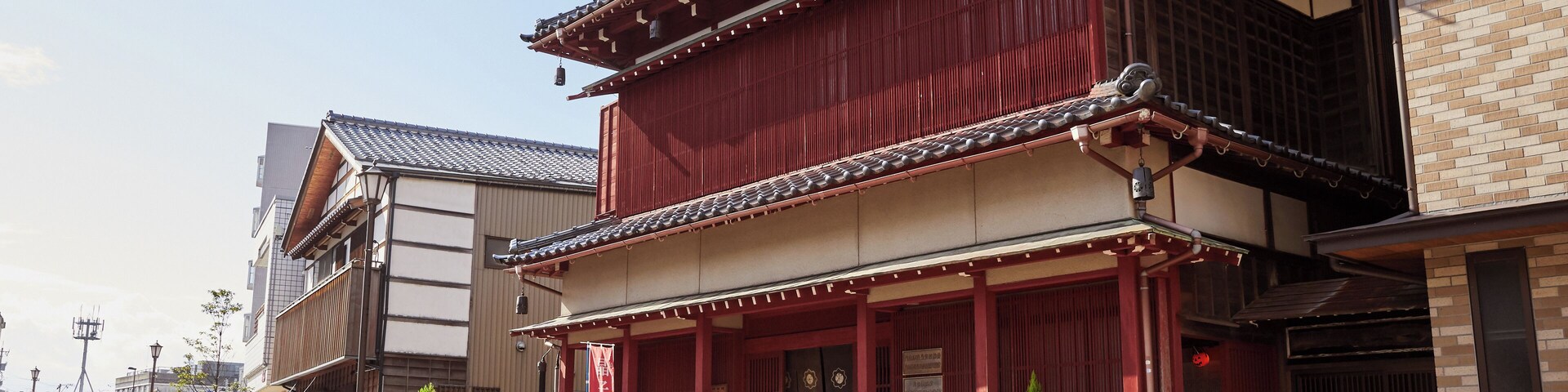 A traditional Japanese building with a red facade, wooden beams, and a tiled roof.