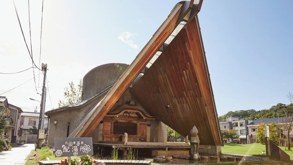 A traditional Japanese building with a slanted roof and a sign in front.