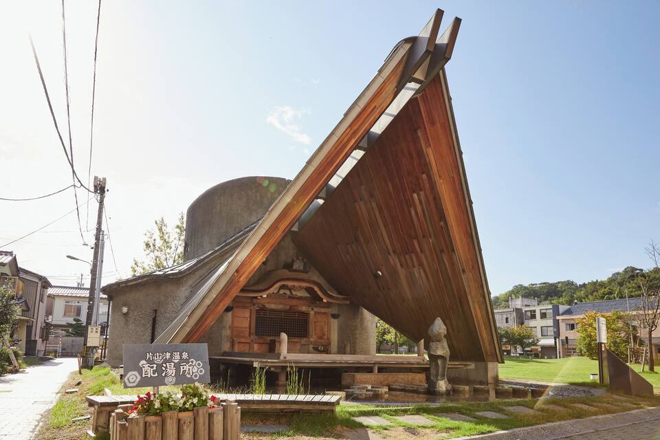 Edifici japonès tradicional amb un teulat inclinat i un rètol al davant.