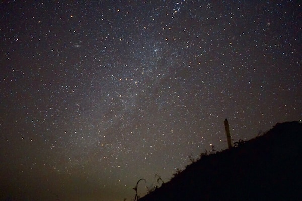 A starry night sky over a hilly landscape.