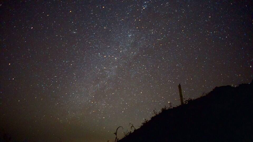 A starry night sky over a hilly landscape.