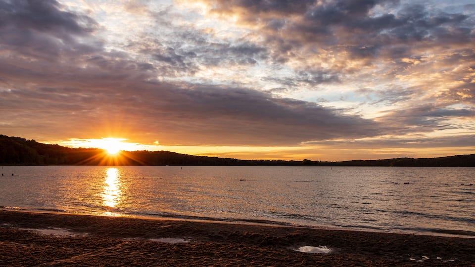 A sunset over a lake with clouds reflecting on the water.