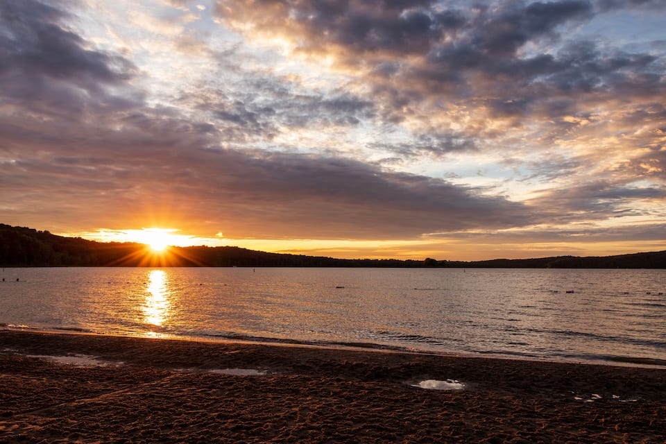 A sunset over a lake with clouds reflecting on the water.