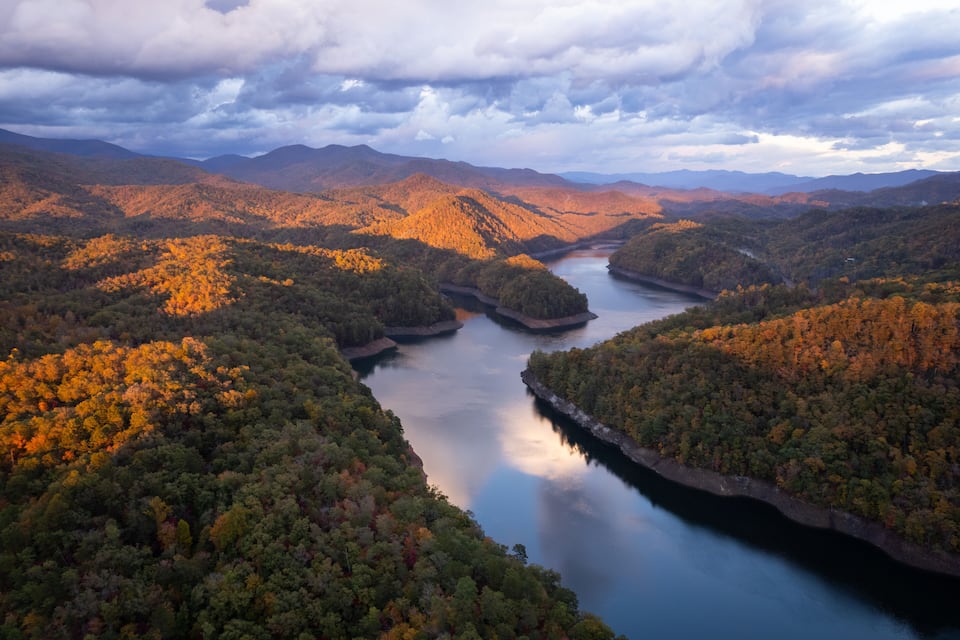 A river winding through a mountainous landscape with autumn foliage.