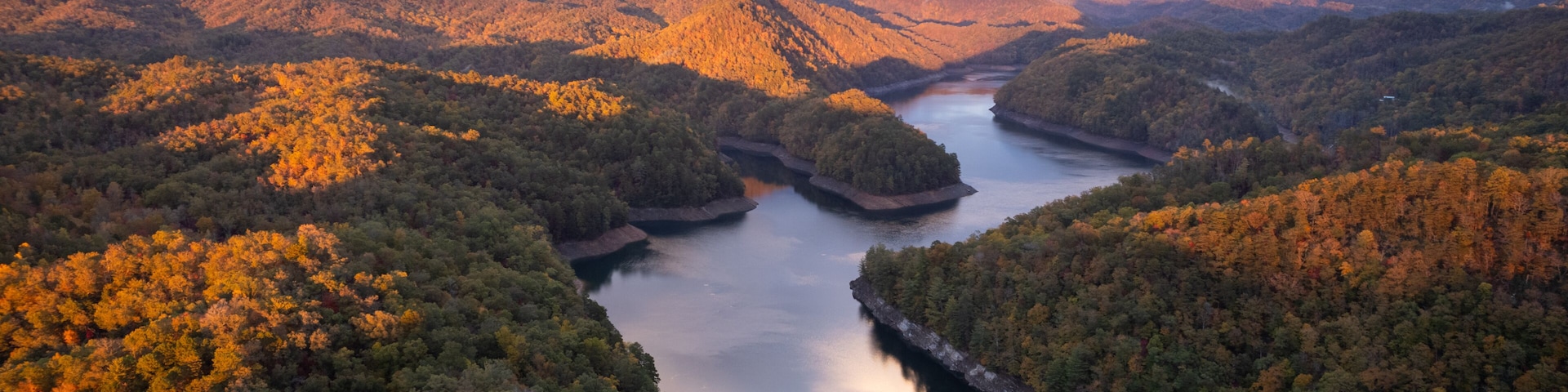 A river winding through a mountainous landscape with autumn foliage.
