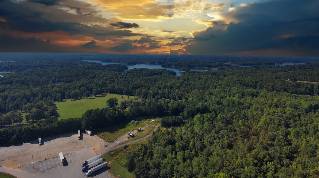 a stunning aerial shot of the blue waters of Lake Hartwell surrounded by vast miles of lush green trees and grass with powerful clouds at sunset in Fair Play South Carolina USA