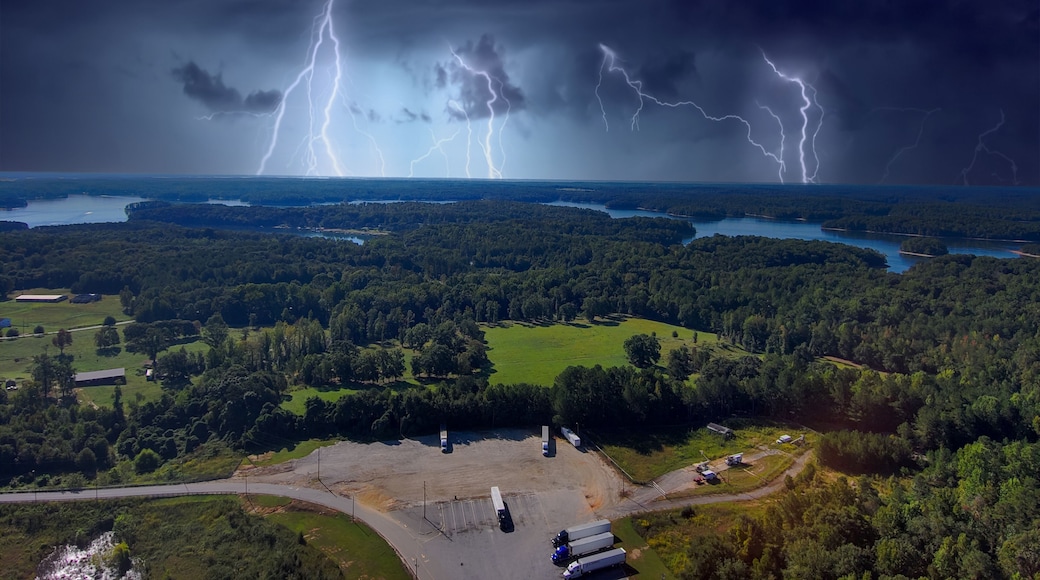 a stunning aerial shot of the blue waters of Lake Hartwell surrounded by vast miles of lush green trees and grass with powerful storm clouds and lightning in Fair Play South Carolina USA
