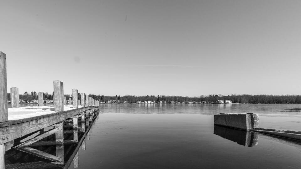 A wooden pier extending into calm water, surrounded by a forested shoreline.