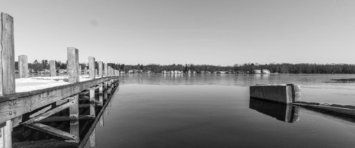 A wooden pier extending into calm water, surrounded by a forested shoreline.