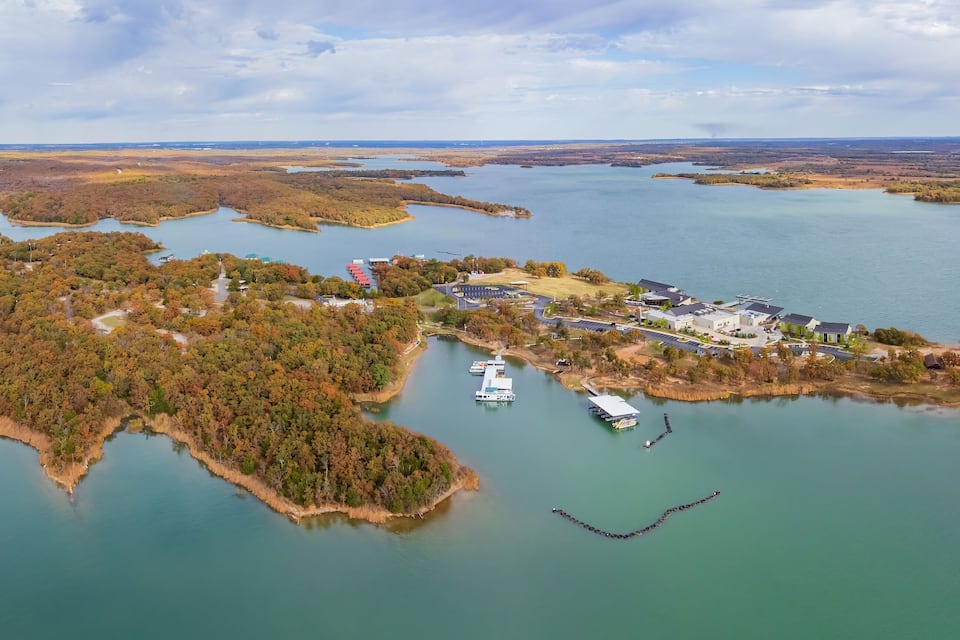 An aerial view of a lakeside community with dense forests, a marina, and residential buildings.