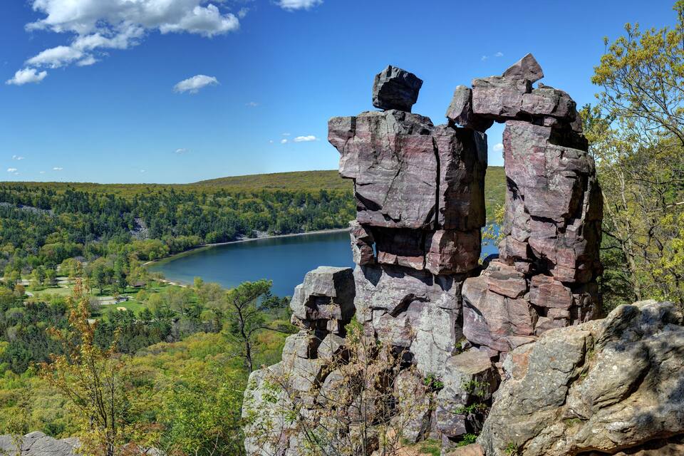 Un afloramiento rocoso con un lago y un bosque al fondo.