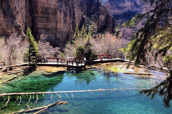 A clear, turquoise pool surrounded by rocky cliffs and trees.