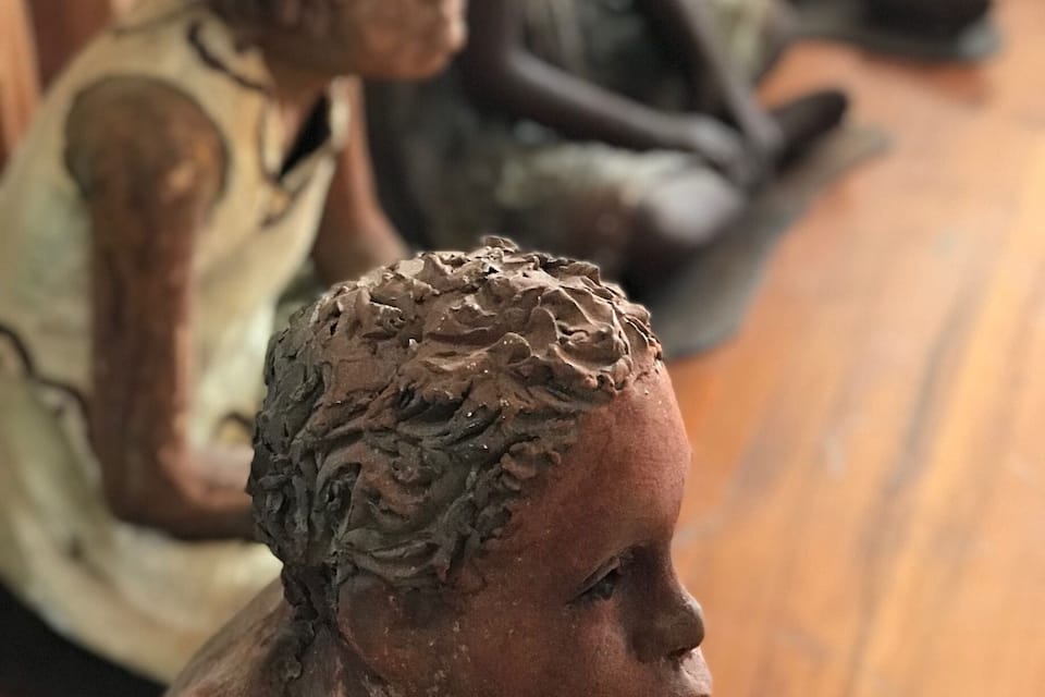 Une rangée de sculptures en bronze représentant des personnages assis.