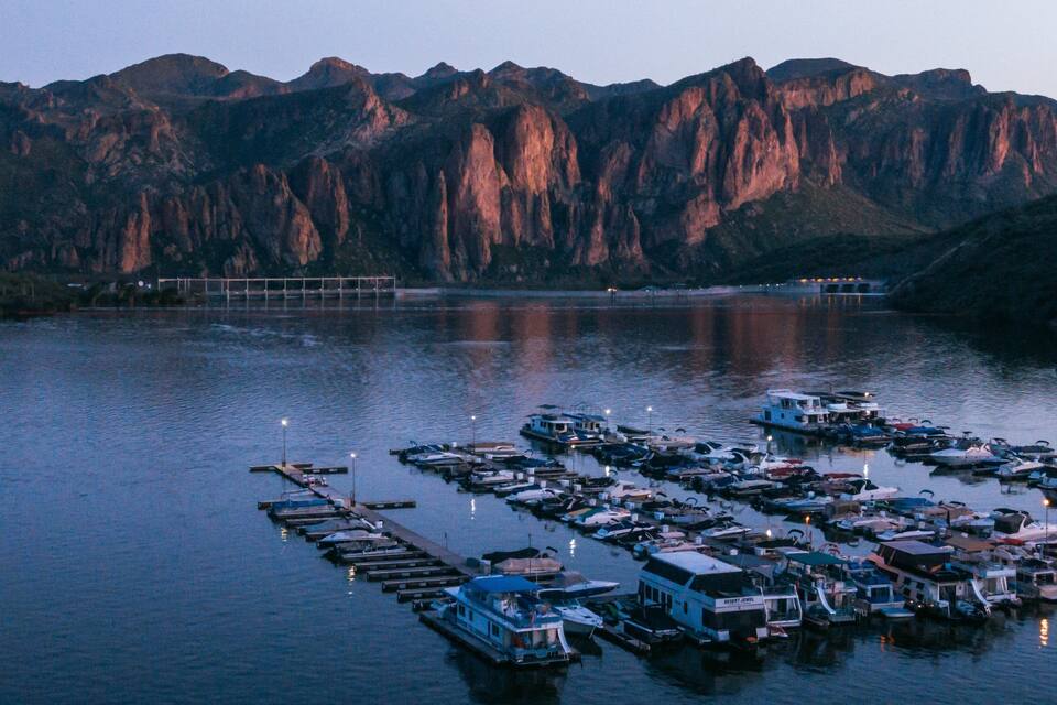 A marina with boats docked in calm waters, surrounded by mountains.