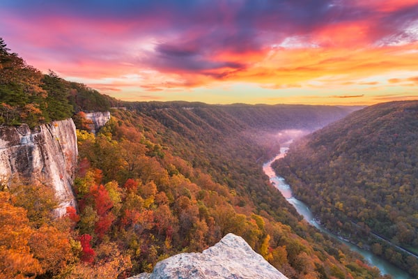 A canyon with a river, autumn foliage, and a rocky cliff.