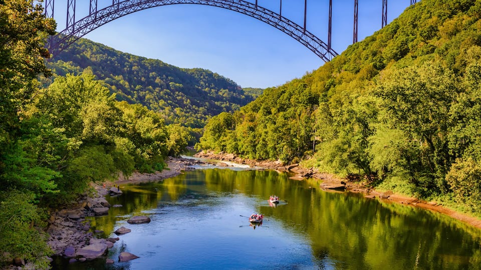 A river with a bridge, surrounded by lush green hills.