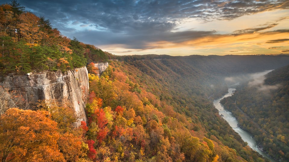 A canyon with a river, autumn foliage, and a cliff.