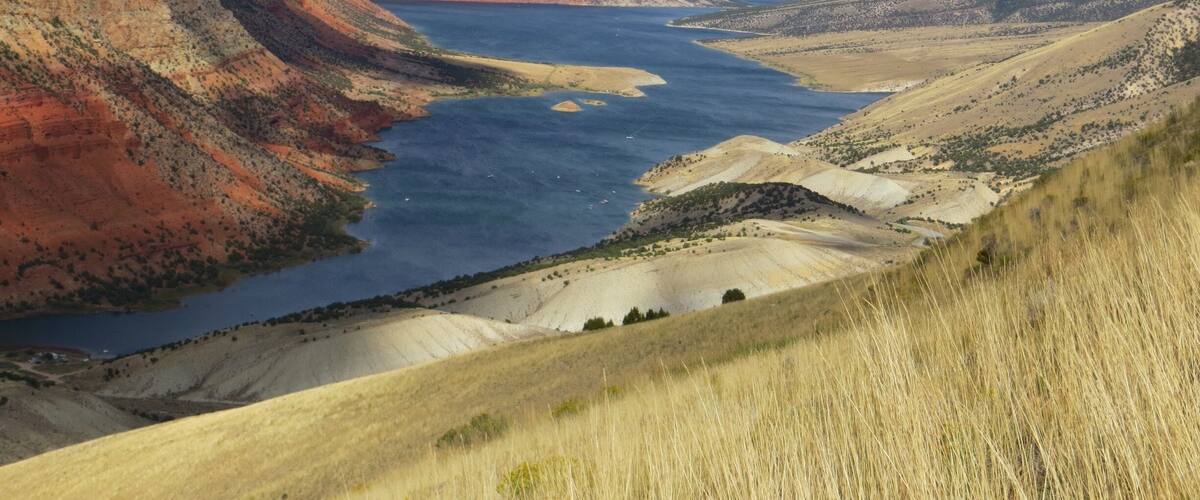 A canyon with a river, red cliffs, and a distant mountain range.