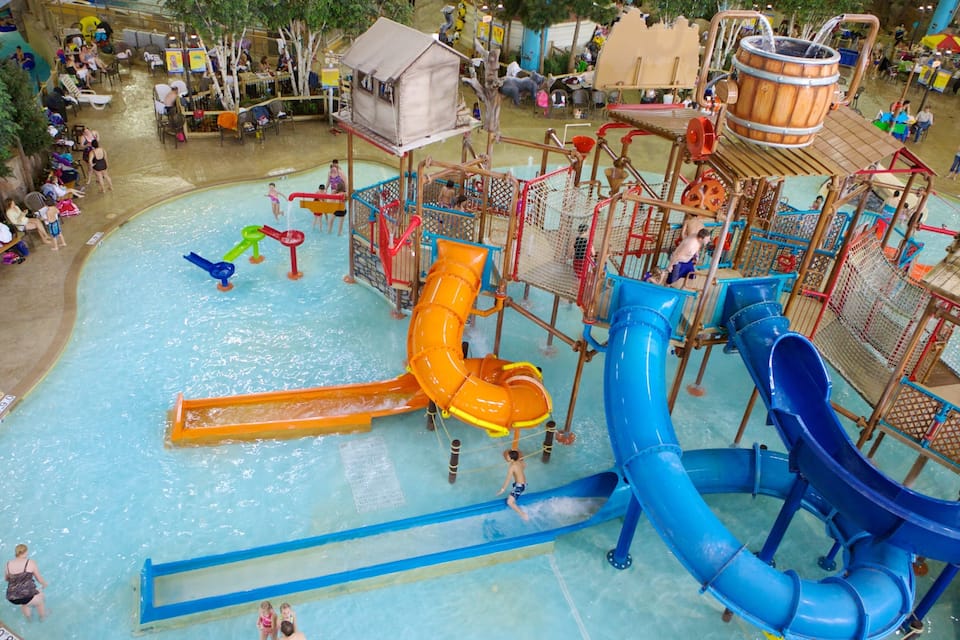 Parque acuático interior con múltiples toboganes y estructuras de juego.