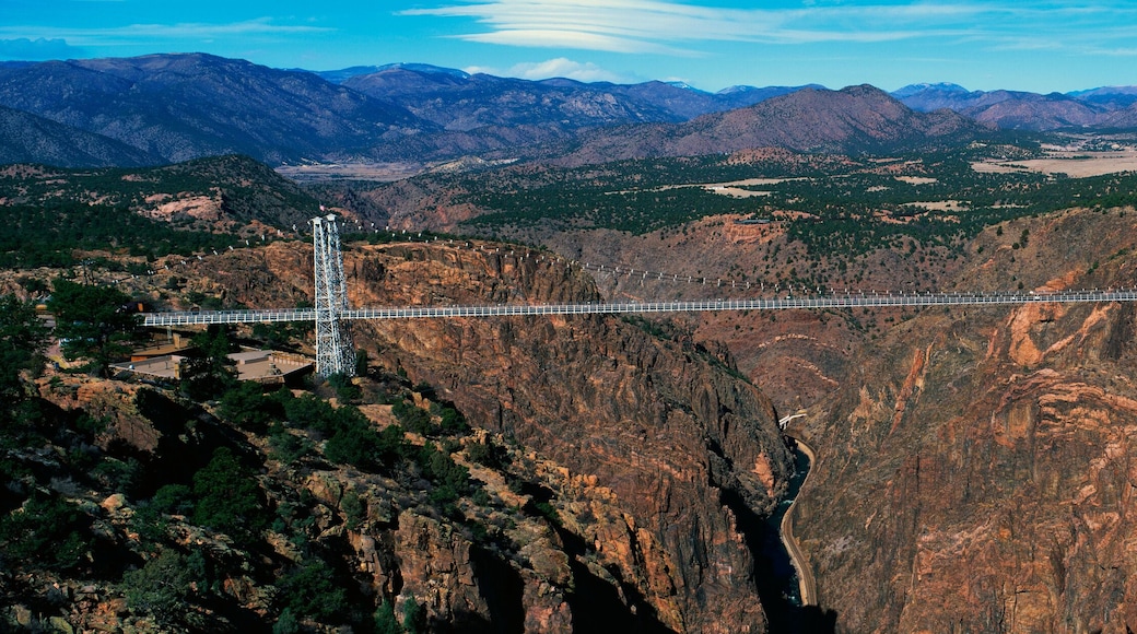 This is the Royal Gorge Bridge which is the world's highest suspension bridge. It is 1053 Ft. above the Arkansas River. Mountains are in the background with red rock below the bridge.