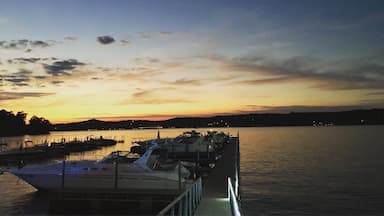 Un puerto deportivo al atardecer con barcos amarrados y una superficie acuática tranquila.