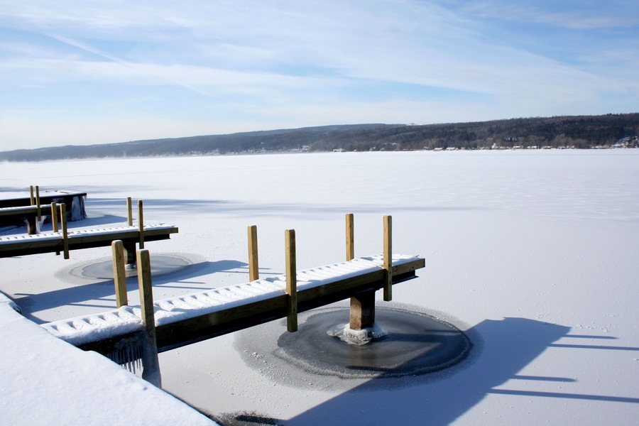 View of snow covered piers on frozen Keuka Lake in the Finger Lakes area of New York. Blue sky, clouds and opposite shore beyond.; Shutterstock ID 71665858